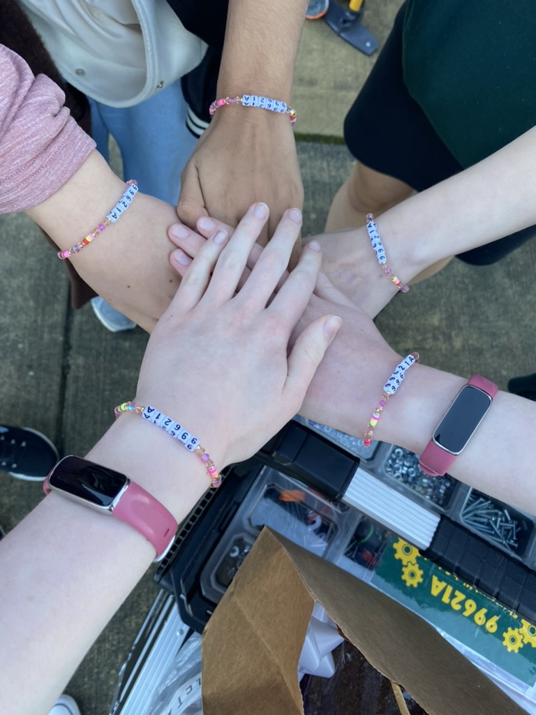 Five hands together. Matching bracelets on all five wrists.