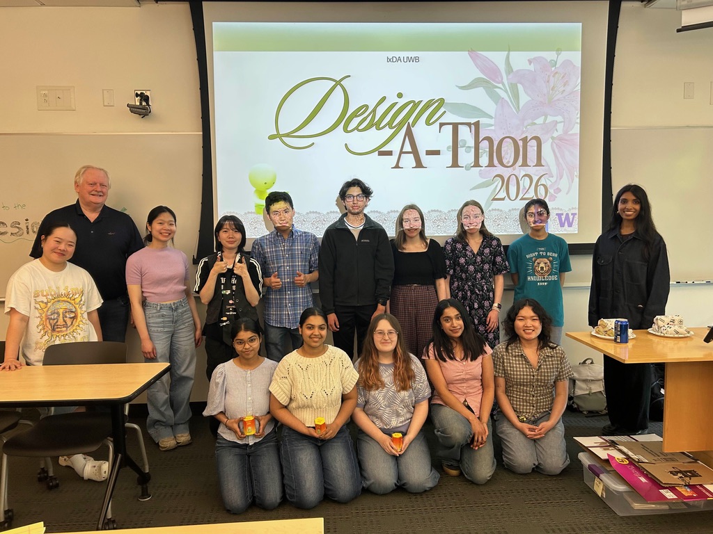 Two rows of people smiling in front of a presentation screen reading Design-A-Thon.