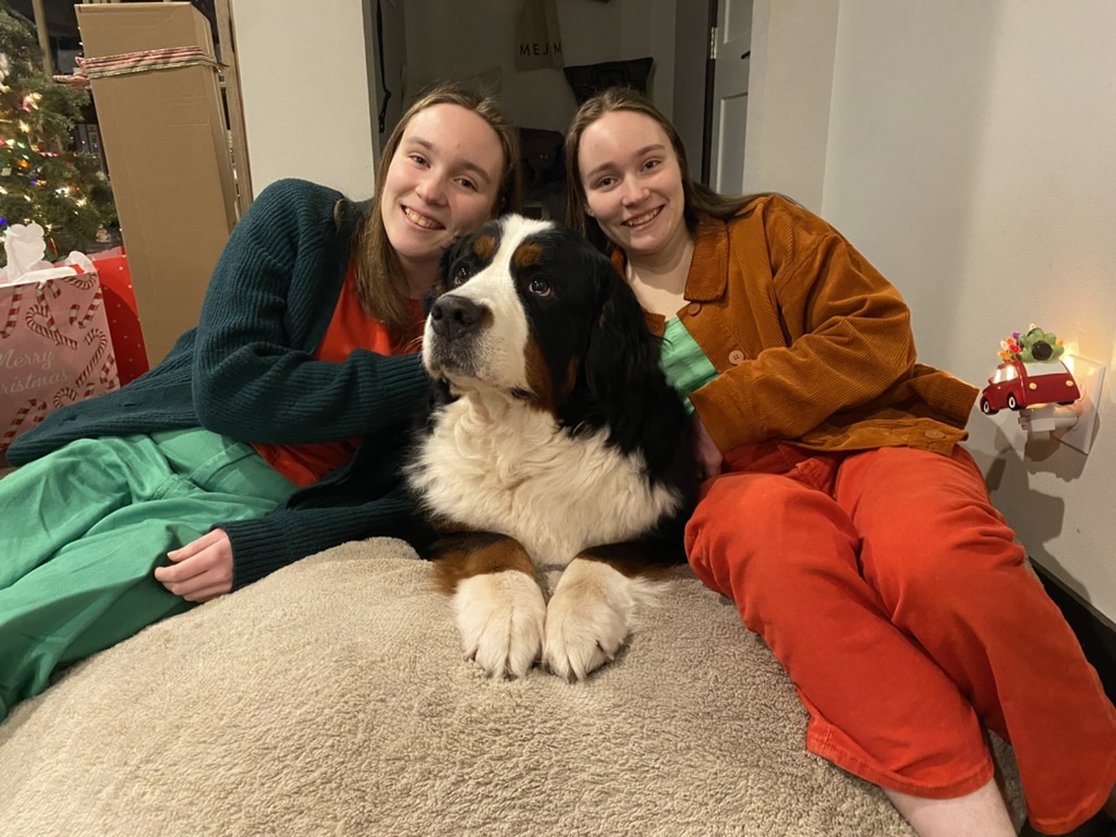 Two girls on a bean bag with a Bernese Mountain Dog.