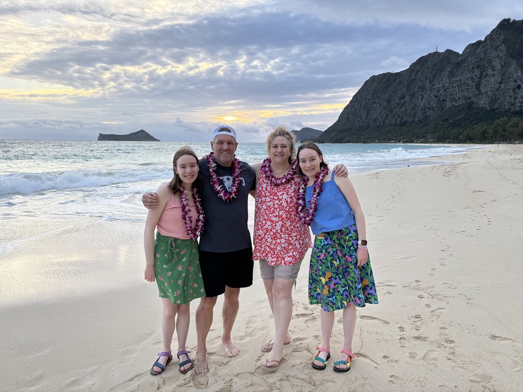 A colorfully dressed family of four on a sandy beach.