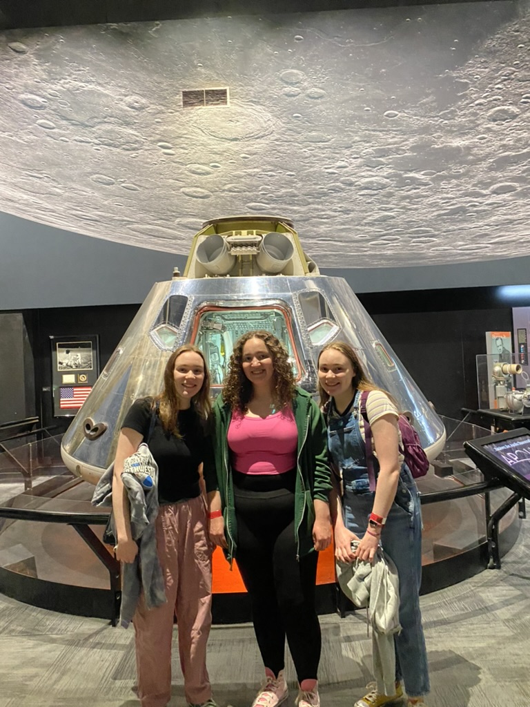 Three girls in a space exhibit at a museum.
