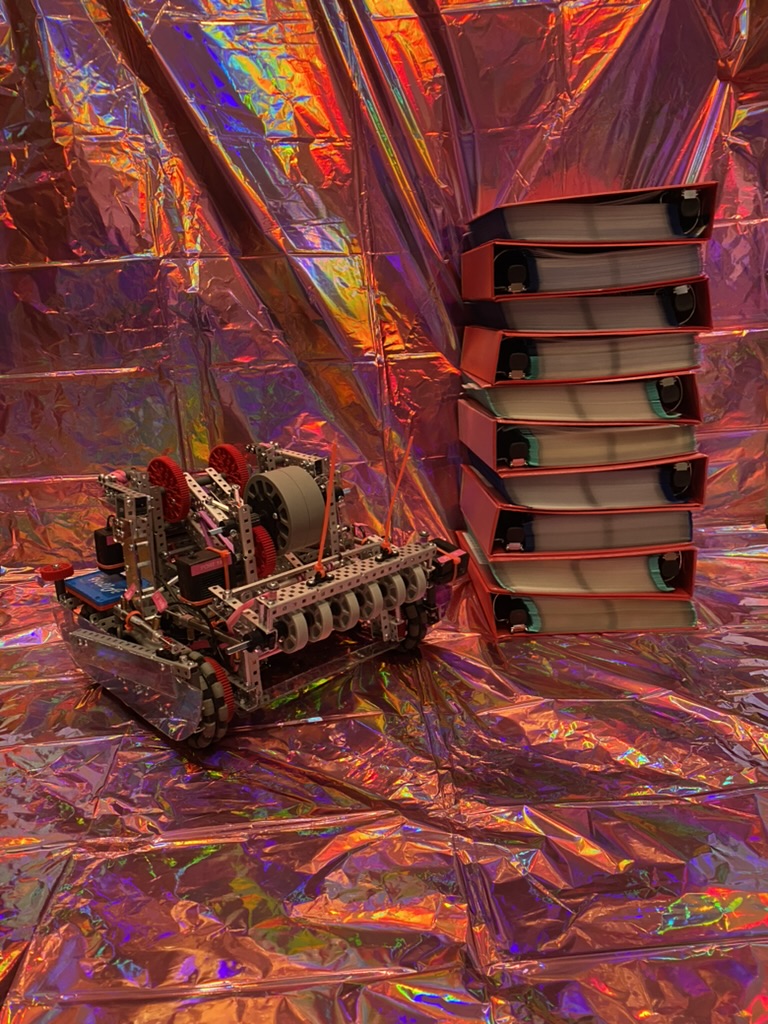 A pink and purple robot next to ten red binders stacked on top of each other.