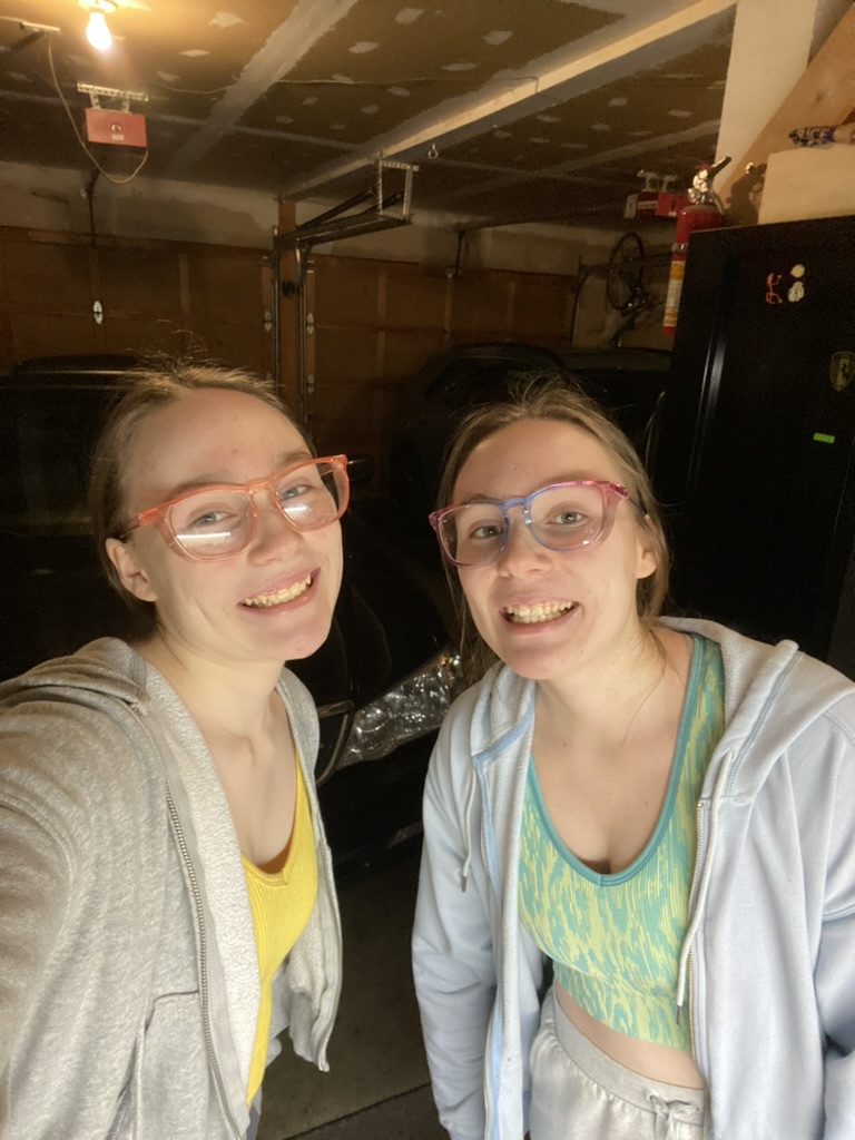 Two girls in safety glasses. One has a pink pair and the other has a rainbow pair.