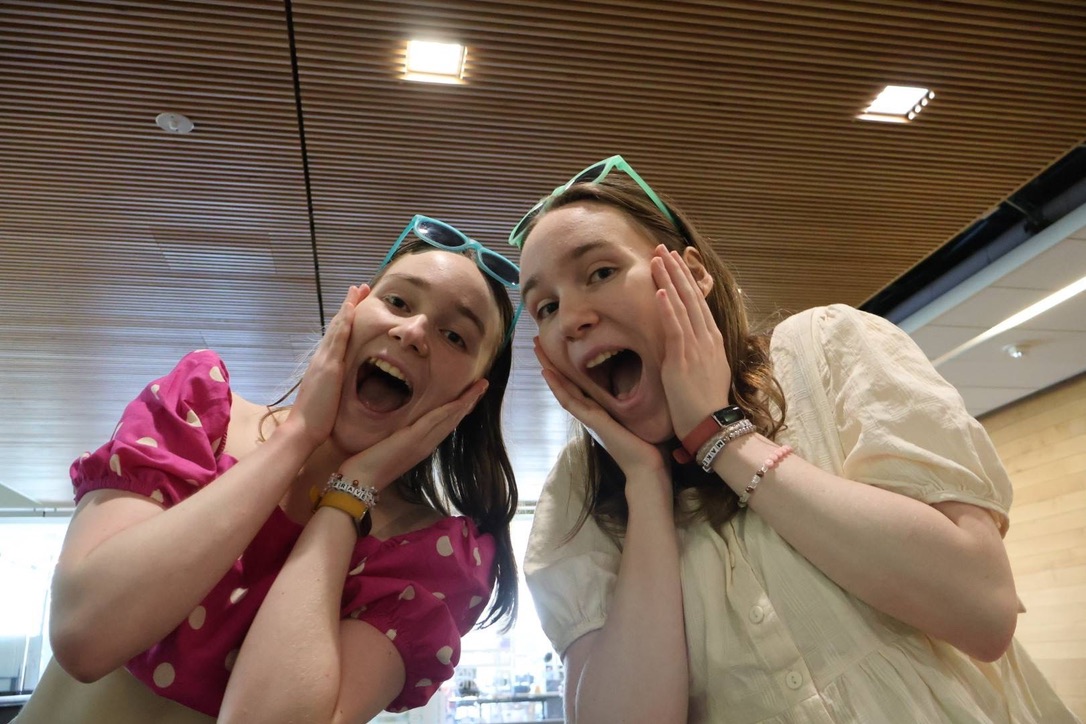 Two girls excitedly smiling with sunglasses on their foreheads.